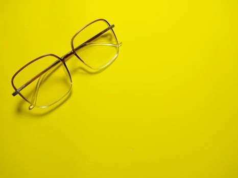 Eyeglasses on yellow background copy space. Gives the concept of wearing eye protection glasses in summer photo