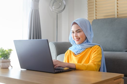 Young happy muslim woman working on laptop in living room at home. photo