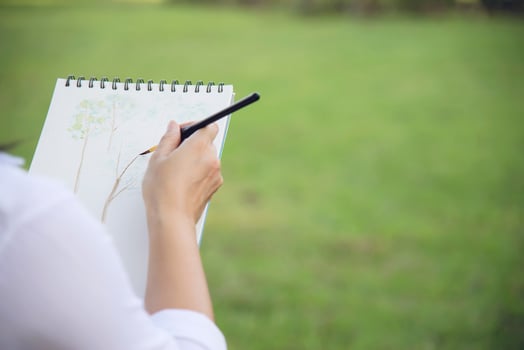 Relax woman painting water colour art work in green garden forest nature - people with creative art in nature stress reduction and meditation concept photo