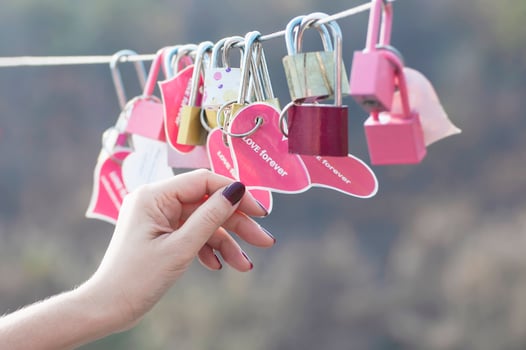 Lady hand holding padlock key with heart symbol of love on bridge - culture of love sign symbol concept photo