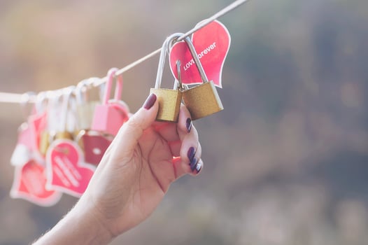 Lady hand holding padlock key with heart symbol of love on bridge - culture of love sign symbol concept photo