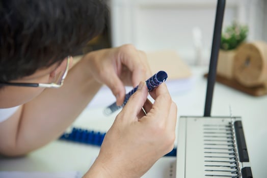 Man making report using comb binding machine - people working with stationary tools concept photo