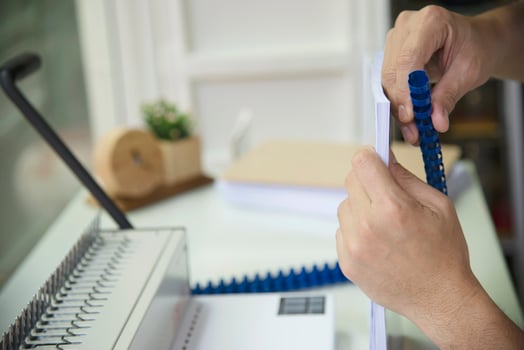 Man making report using comb binding machine - people working with stationary tools concept photo