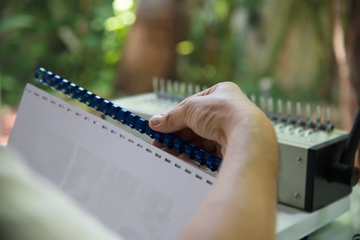 Man making report using comb binding machine - people working with stationary tools concept photo