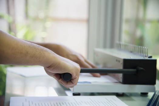 Man making report using comb binding machine - people working with stationary tools concept photo