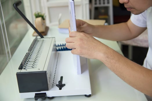 Man making report using comb binding machine - people working with stationary tools concept photo