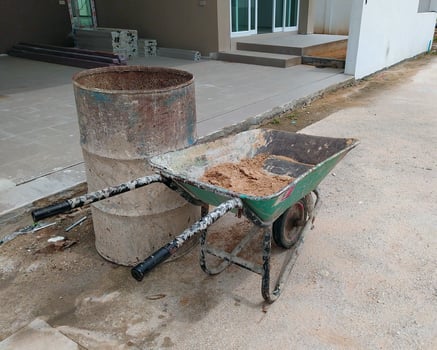 The old Wheelbarrow and the old iron barrel in front of the unfinished building. photo