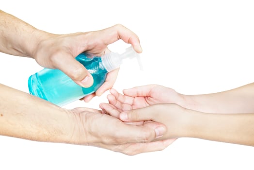 Closeup of father hand pushing alcohol sanitizer gel pump dispenser to son hand isolated over white background - people with alcohol sanitizer prevent bacteria and COVID-19 virus protection concept. photo