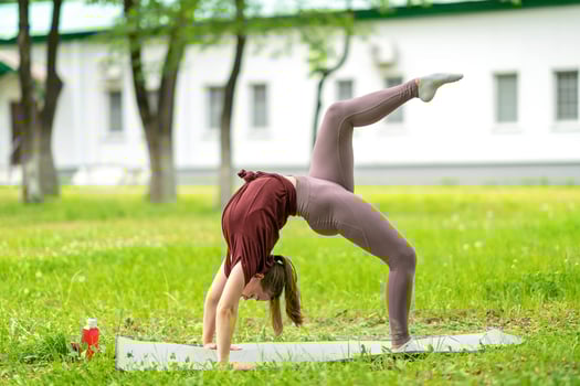 Young girl having online workout outdoors using laptop. Pilates or yoga video lesson on internet. Happy smiling girl practicing pilates lesson online in garden outdoors during quarantine. photo