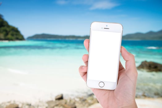 Woman hand showing a blank smart phone with isolated screens display on the beach background photo