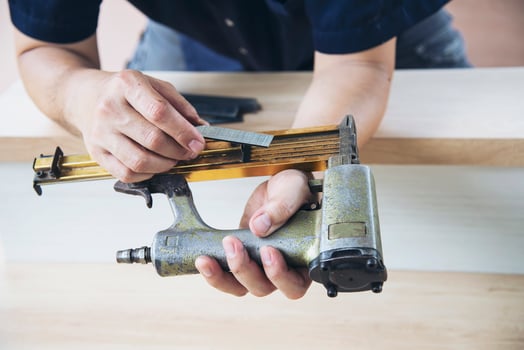 Carpenter using air nail gun doing wooden furniture work photo