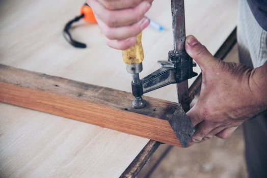 Carpenter doing wood work using clamping hand tool photo