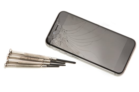 Broken smartphone and small screwdrivers for repair photo