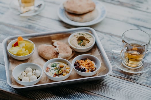 Overhead image of traditional Israel food on tray. Hummus, domestic goat cheese, tomatoe core, beetroot with spices, pita bread, beverage in glass photo