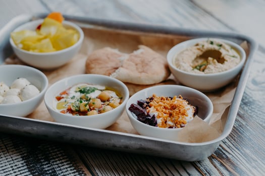 Food and nutrition concept. Traditional Israel dish for dinner. Tray of delicious hummus, beet with spices, core of tomatoes, pita bread, goat cheese served for you photo
