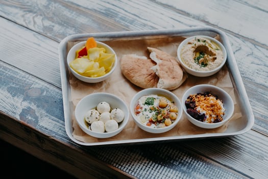 Traditional Israel food concept. Bowl of exotic dish on tray. Hummus, vegetables with spices. Pita bread. Delicious breakfast. Goat cheese. photo