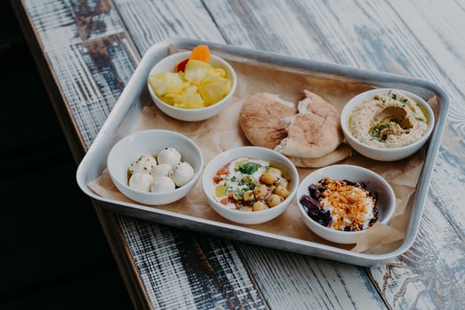 Traditional Israel cuisine concept. Top view of tasty exotic dishes served on tray. Pita bread, vegetables on grill, goat cheese, hummus on wooden table photo