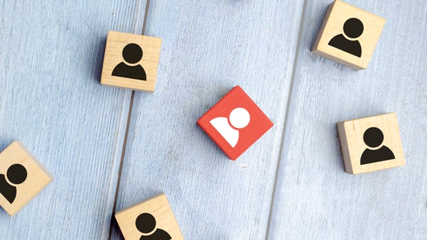 Red wooden cube with person icon stand out from the crowd on blue background. photo