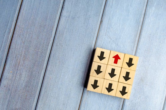 Wooden block with red arrow facing the opposite direction black arrows photo