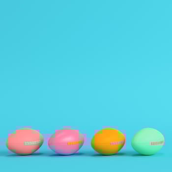Four colorful american football balls on bright blue background in pastel colors. photo