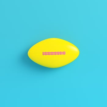 Yellow american football ball on bright blue background in pastel colors photo