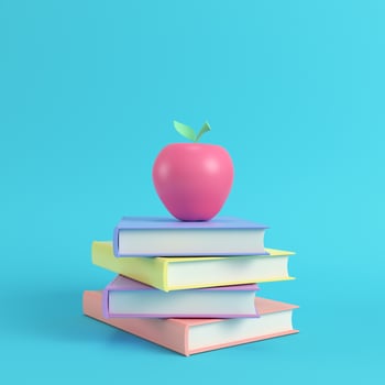 Pink apple on a stack of books on bright blue background in pastel colors photo