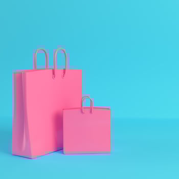 Pink shopping bags on bright blue background in pastel colors photo