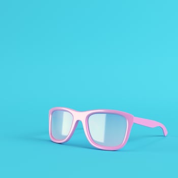 Pink sun glasses on bright blue background in pastel colors photo