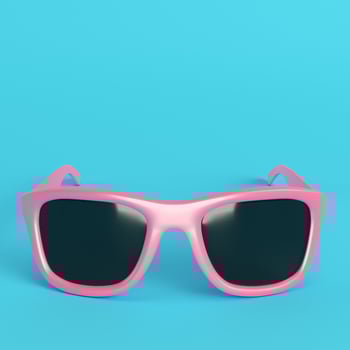 Pink sun glasses with black lenses on bright blue background in pastel colors photo