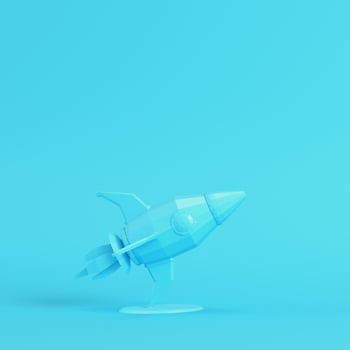 Rocket with stand on bright blue background in pastel colors. Minimalism concept photo