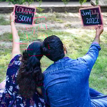Indian couple posing for maternity baby shoot. The couple is posing in a lawn with green grass and the woman is falunting her baby bump in Lodhi Garden in New Delhi, India photo