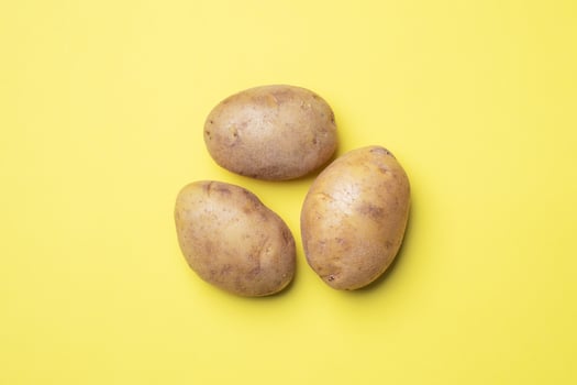 Raw potato tubers on a yellow background. photo