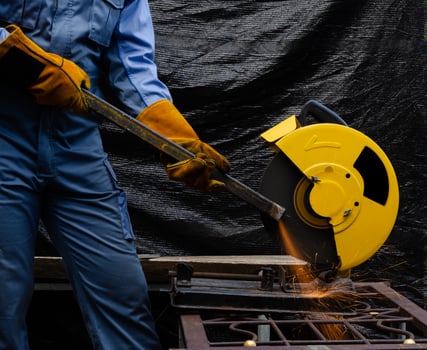 Worker grinding hollow structural steel with circular abrasive saw tool photo