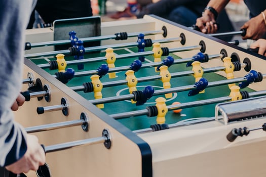 Friends play table football game, spend free time in entertainment center. Recreation and leisure concept. Active players. Sport games photo