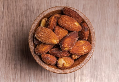 Salted almonds in a wooden cup. Healthy food concept, top view. photo