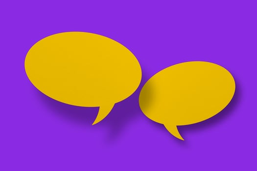 Speech balloon shaped yellow paper against purple background. photo
