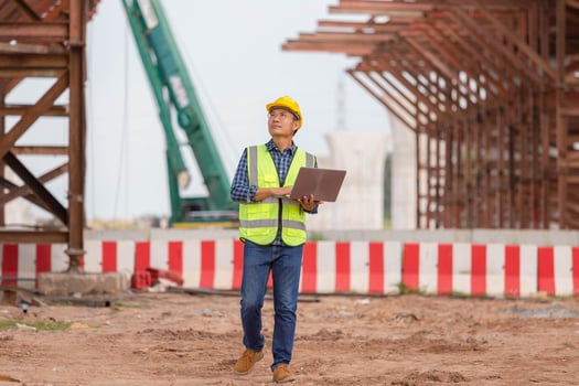 Engineer checking project at the building site, Man in hardhat with laptop at the infrastructure construction site photo