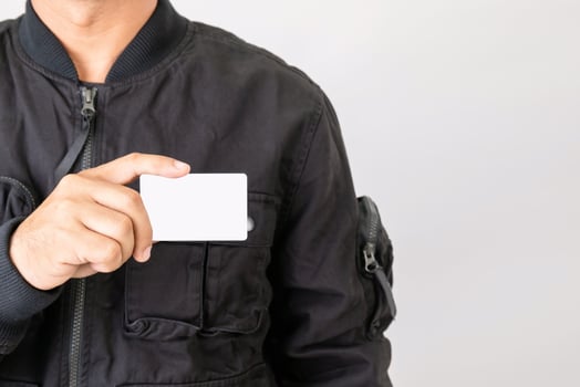 Portrait rider in black jacket holding and show blank of Thailand driving licence. Studio shot isolated on grey photo