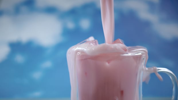 Close up double glass cup with pouring motion of  pastel pink color drink with blue sky background, pastel theme photo