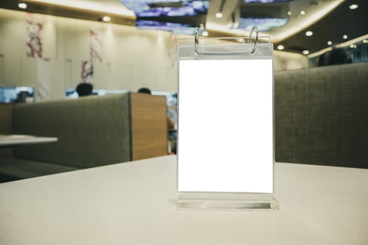 Mockup empty white label menu frame on table with cafe restaurant interior background photo