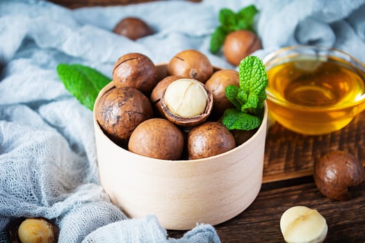 Macadamia nuts in shell with mint leaves and honey on wooden background photo