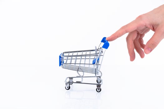 Female hand with fingers pushing a shopping cart isolated on white background. Copy space. photo