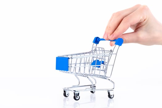 Female hand with fingers pushing a shopping cart isolated on white background. Copy space. photo
