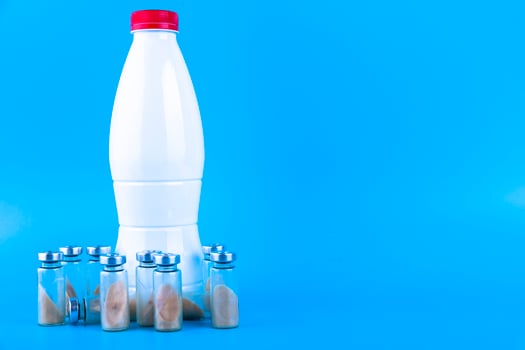Vials, ampoules with dry probiotic, bifidobacteria and a bottle with milk on a blue background. Copy space. photo