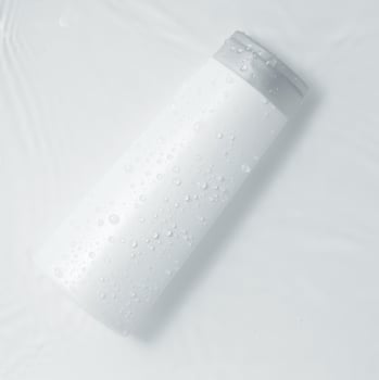 White cosmetic bottle on the water surface. Blank label for branding mock-up. Flat lay, top view. photo