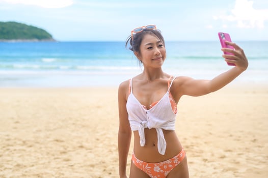 Young Beautiful woman in Bikini listening to music and using smartphone on the beach,  Summer, vacation, holidays, Lifestyles concept. photo