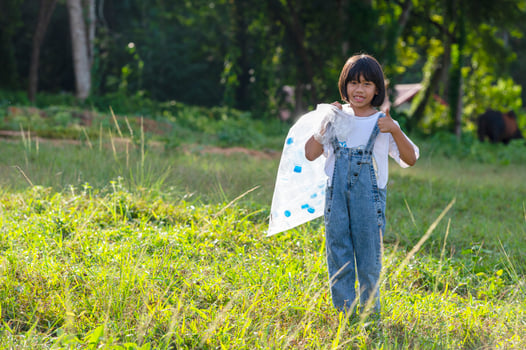 Asian children volunteer to put plastic bottles in garbage bags. Volunteer concept and ecology photo