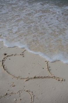 hearts drawn on the sand of a beach photo