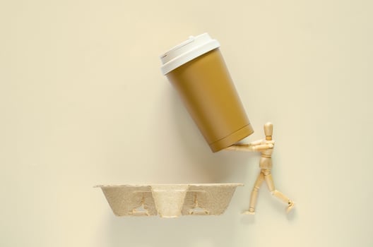 Wooden model holding reuse coffee tumbler to put on recycle paper tray. World environment day concept. photo