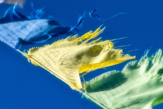 Blue, yellow and green Tibetan Buddhist prayer flags waving in t photo